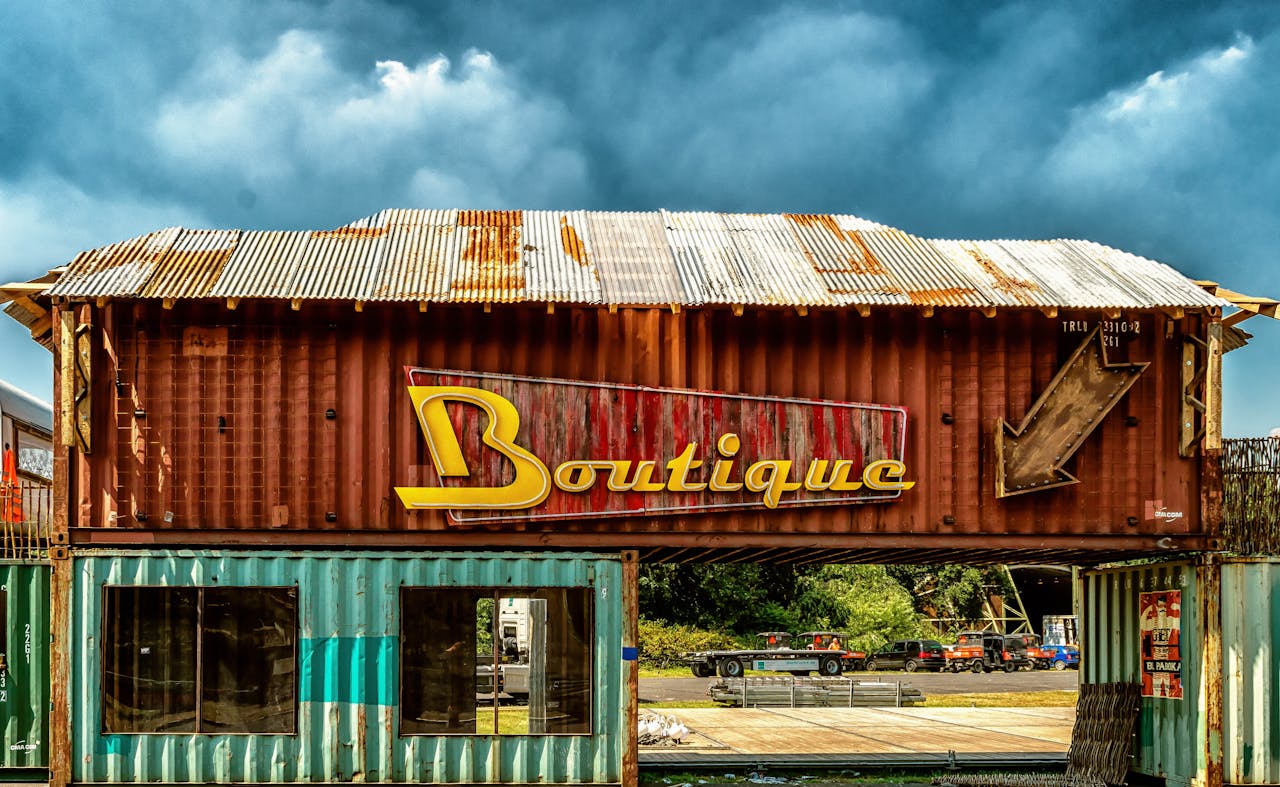 Vintage boutique sign on rustic shipping container under cloudy sky, outdoors.
